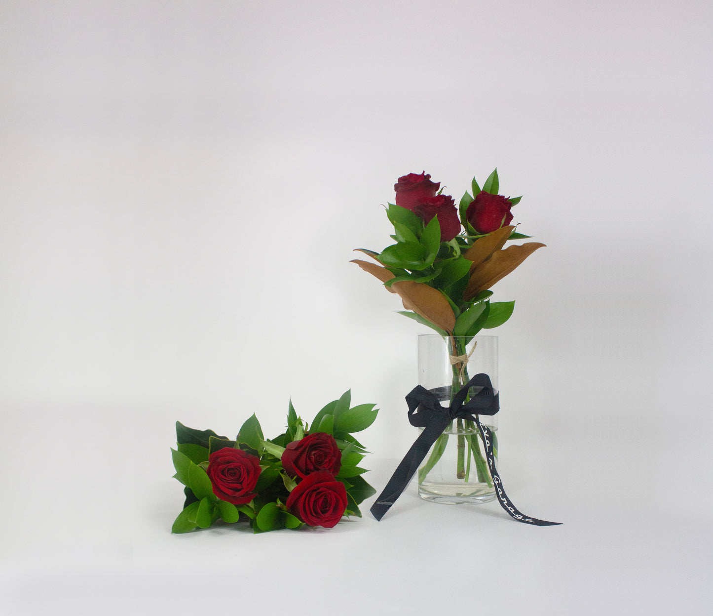 Romantic bouquet of red roses in a clear vase with a black ribbon on a white background