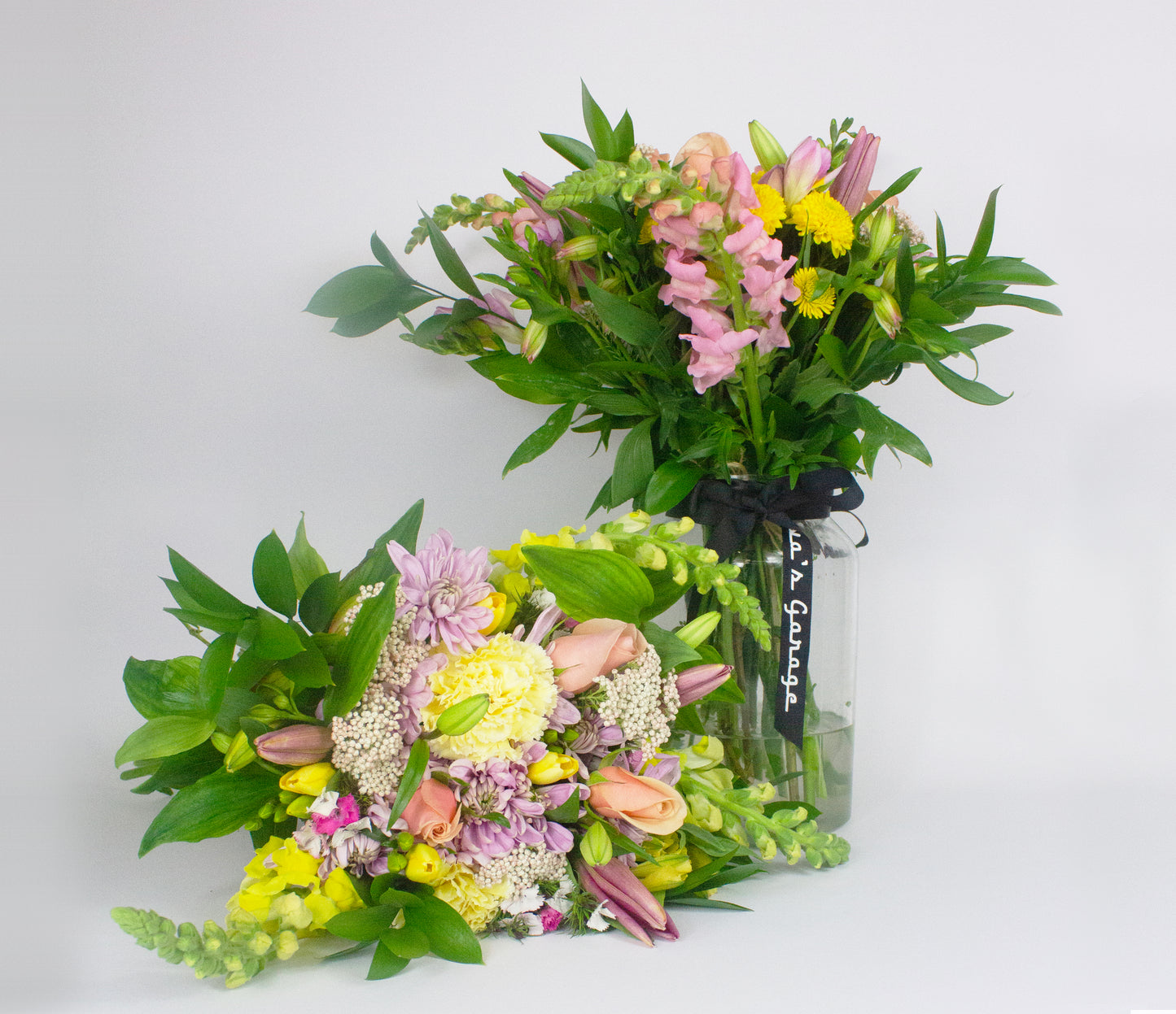 Two floral bouquets in a clear vase on a white background