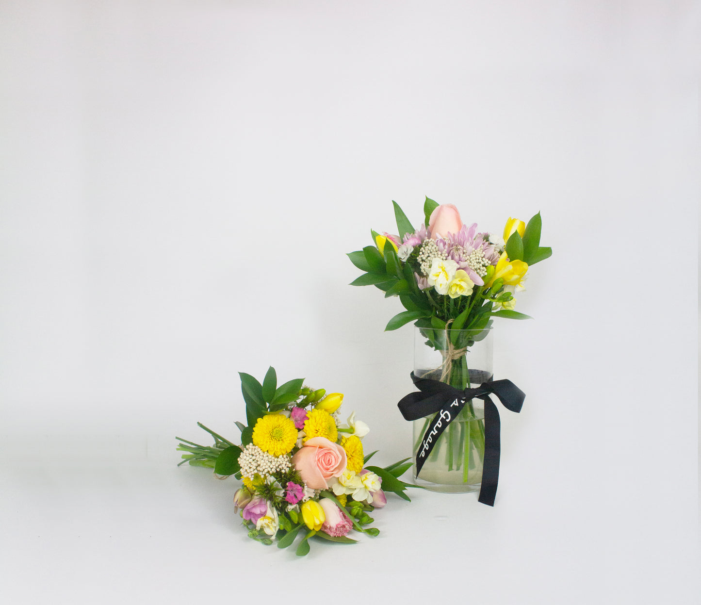 Two small floral arrangements in glass jars on a white background